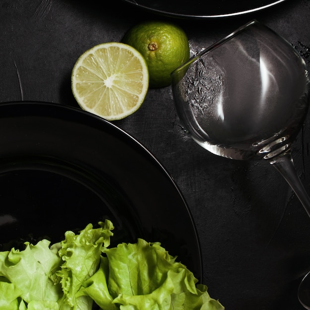 Platos y copa de vino sobre fondo negro con contraste de color verde. Cena elegante en un restaurante. Concepto de arte y diseño