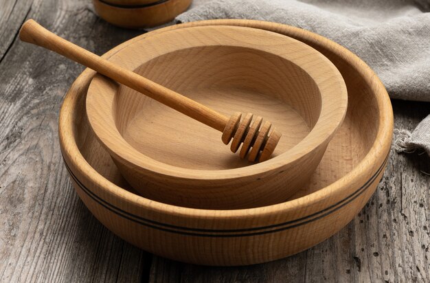 Platos y cucharas de madera redondas vacías en la mesa gris, palo de miel, cerrar