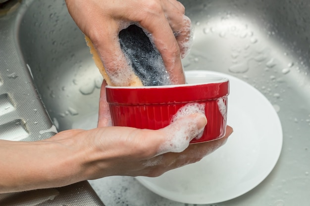 Foto los platos se limpian con una esponja en la espuma.