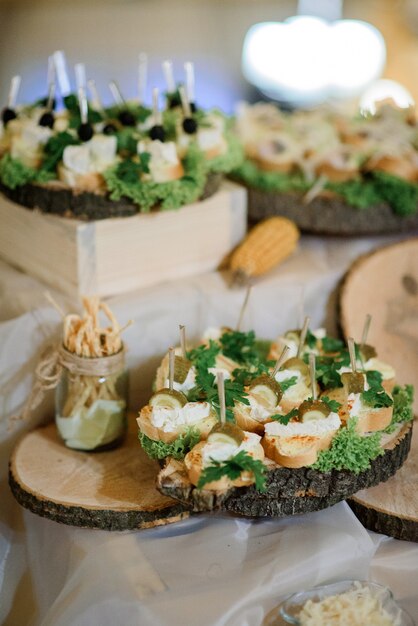 Platos de madera con aperitivos decorados con vegetación se levantan en diferentes capas de la mesa