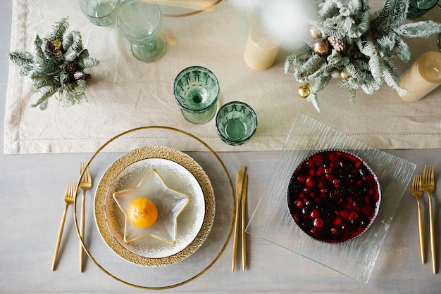 Platos de oro y blanco, un plato en forma de estrella con mandarina. Tarta de bayas en la mesa