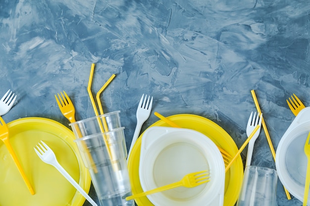 Platos de plástico sobre fondo azul. Copie el espacio. Contaminación ambiental.