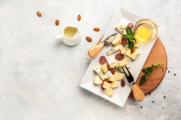 Platos de queso servidos con uvas, miel y nueces sobre una tabla de madera. banner, menú, lugar de receta para texto, vista superior.