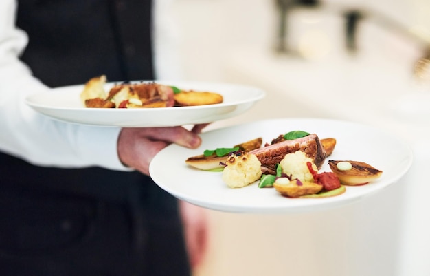 Platos de restaurante y mesero sirviendo comida para cenas elegantes, comida de lujo y cita elegante para el día de San Valentín Cena de servicio de hospitalidad y servidor con cena para una fiesta o celebración formal