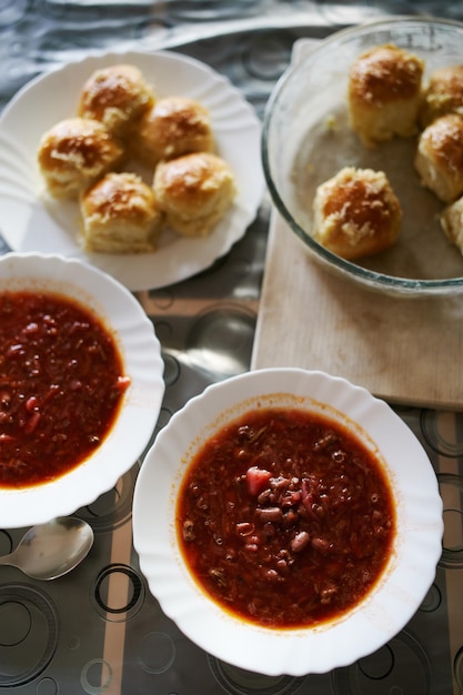 Los platos con rosquillas están al lado de los platos de borsch en la mesa