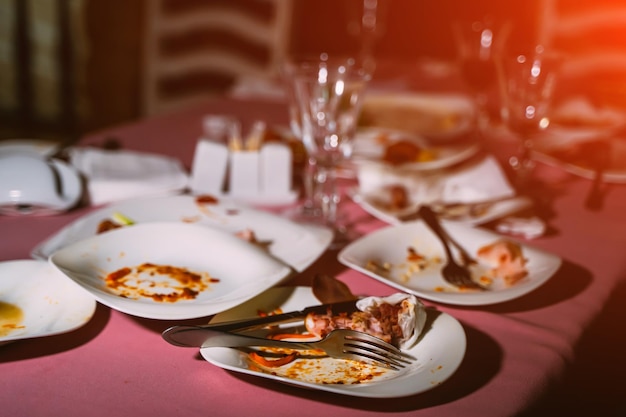 Platos sucios con tenedores y cuchillos y vasos vacíos en la mesa después de la celebración Comida sobrante después de la fiesta Primer plano