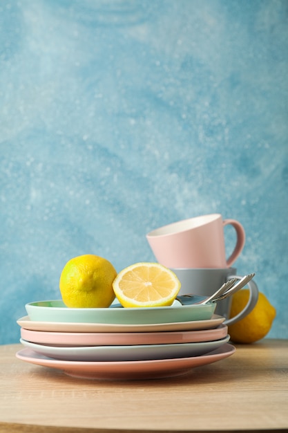 Platos y tazas con limones apilados en mesa de madera, espacio para texto