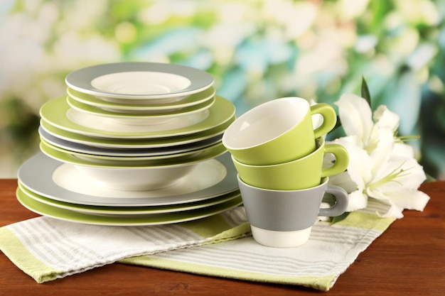 Platos y tazas vacíos en la mesa de madera sobre fondo verde