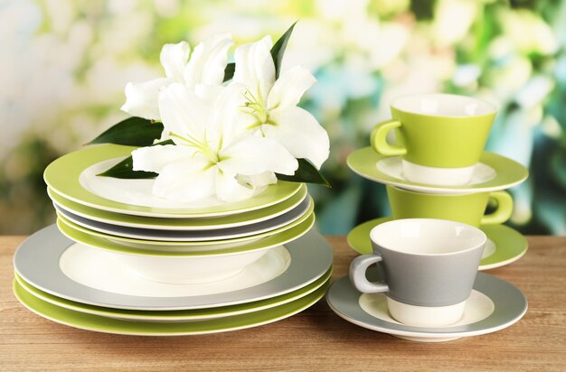 Platos y tazas vacíos en la mesa de madera sobre fondo verde