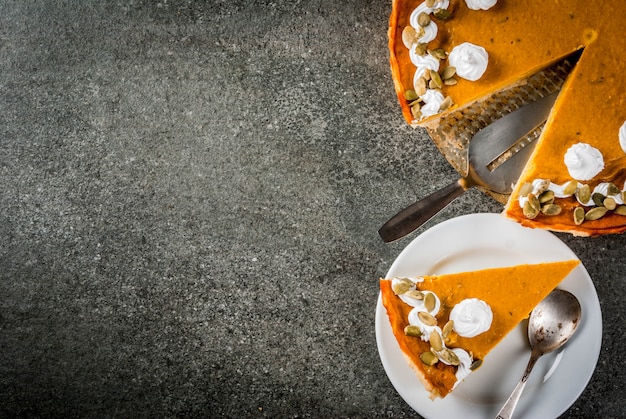 Platos tradicionales de otoño. Halloween, Acción de Gracias. Rodajas de pastel de calabaza picante con crema batida y semillas de calabaza en la mesa de piedra negra. Vista superior copyspace