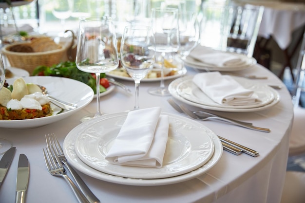 Platos y utensilios para la comida en la mesa festiva. Hermosos vasos de vidrio cerca de platos y comida festiva.