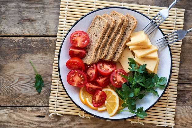 Platte des Kirschtomaten-, Käse- und Roggenbrotes auf einem Holztisch