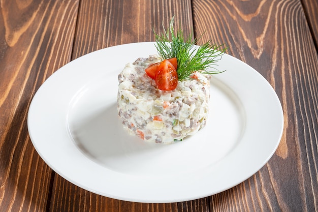 Platte des traditionellen russischen Salats Olivier auf Holztisch