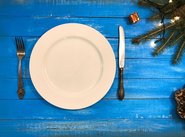 Platte, Gabel und Messer auf einer blauen Holzoberfläche, Draufsicht