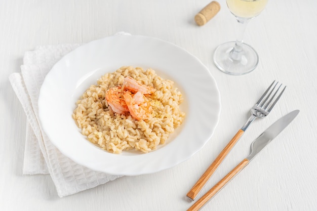 Foto platte mit cremigem italienischem risotto aus arborio-reisgarnelen und käse, serviert mit wein auf dem tisch