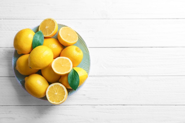 Platte mit frischen Zitronen auf Holztisch