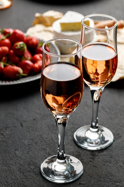 Platte mit frischer Erdbeere und Glas Wein auf schwarzem Hintergrund schließen oben