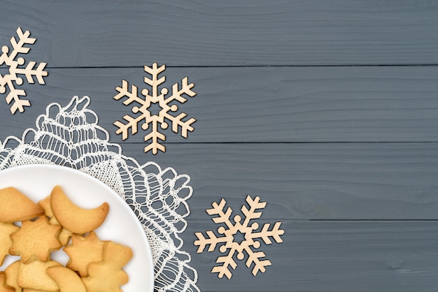 Platte mit geschmackvollen Weihnachtsplätzchen mit dekorativen Schneeflocken auf Holztisch