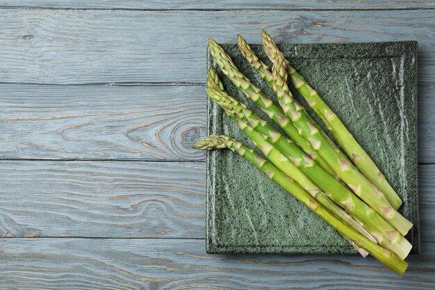 Platte mit grünem Spargel auf hölzernem Hintergrund