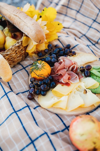 Platte mit Hartkäse-Radomer-Schinken und Trauben auf einem Bett mit frischem Baguette und gelben Blättern