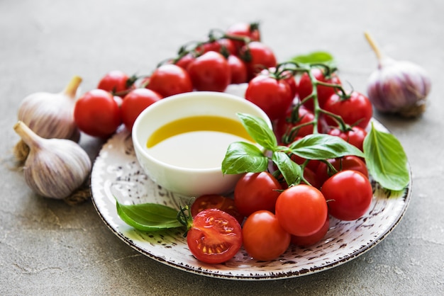 Platte mit Kirschtomaten, Olivenöl und Basilikum