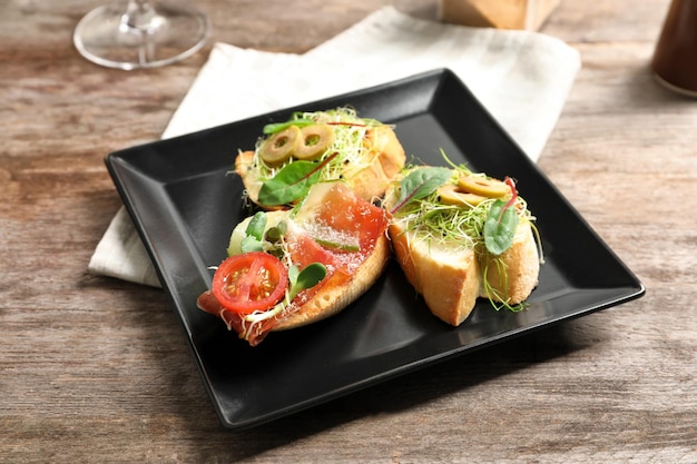 Platte mit köstlichen Bruschettas auf Holztisch