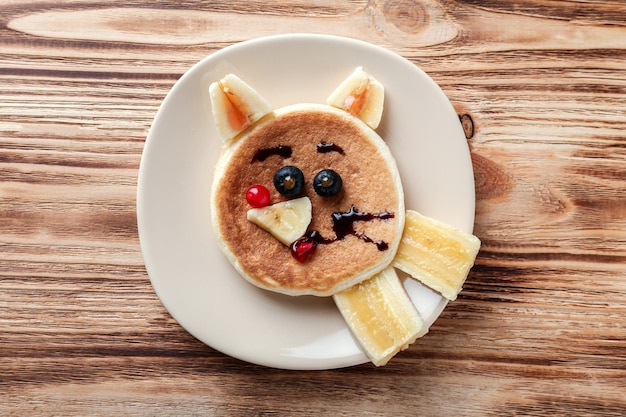 Platte mit kreativem hausgemachtem Pfannkuchen auf Holztisch