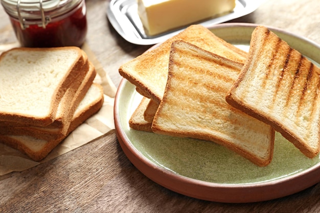 Platte mit leckerem geröstetem Brot auf Holztisch