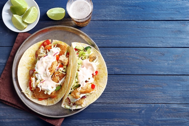 Platte mit leckeren Fischtacos auf Holztisch