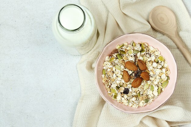 Platte mit müsli, flasche milch und holzlöffel auf grau