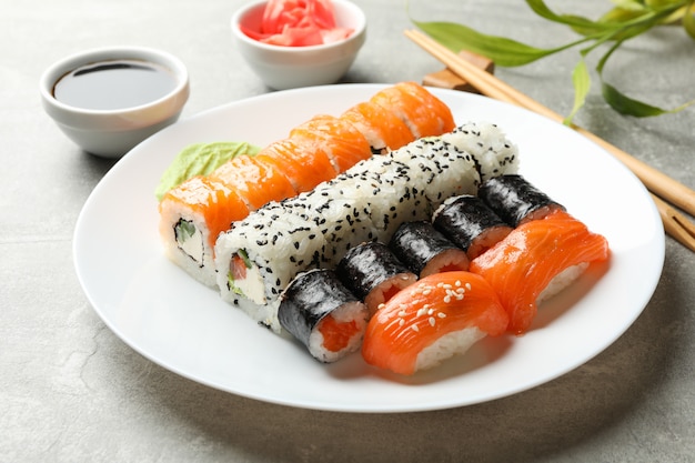 Platte mit Sushi-Rollen auf grauer Oberfläche. japanisches Essen