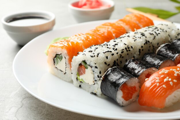 Platte mit Sushi-Rollen auf grauer Oberfläche. japanisches Essen