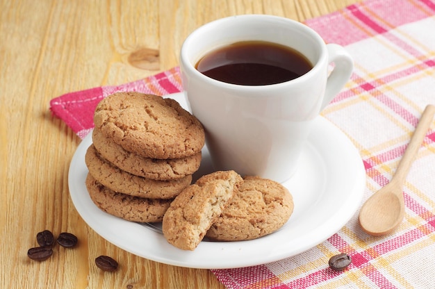 Platte mit tasse kaffee und haferkeksen auf holztisch