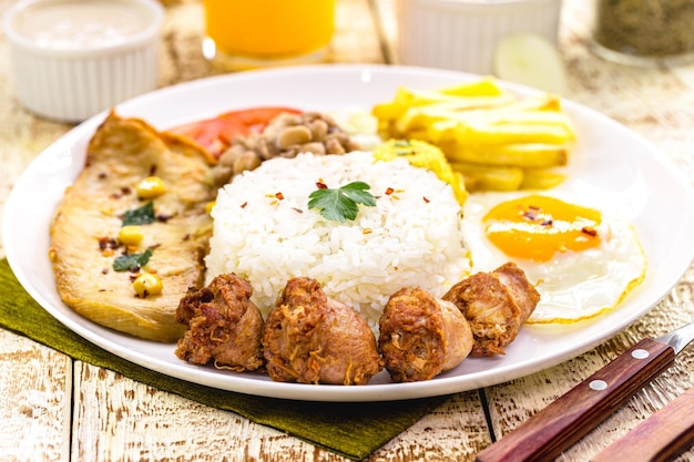 Platte mit typisch brasilianischer Essenswurst und gebratenem Hühnerreis mit Bohnen und Salat Farofa und Spiegelei