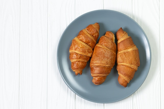 Platte von frisch gebackenen Croissants auf weißer hölzerner Tischoberansicht