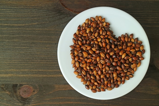 Platte von gebratenen Gerstenkörnern auf Holztisch