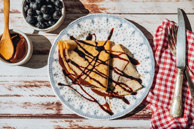 Platte zwei exquisite hausgemachte Pfannkuchen oder Crêpes gefüllt mit Mandelcreme und Schokolade mit Schokoladenfäden, die Luftbild-Gesamtaufnahme bedecken