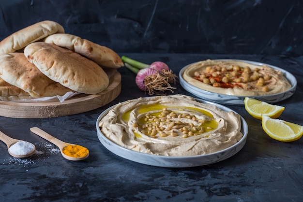 Platten von Hummus mit Pita-Brot auf schwarzem Hintergrund