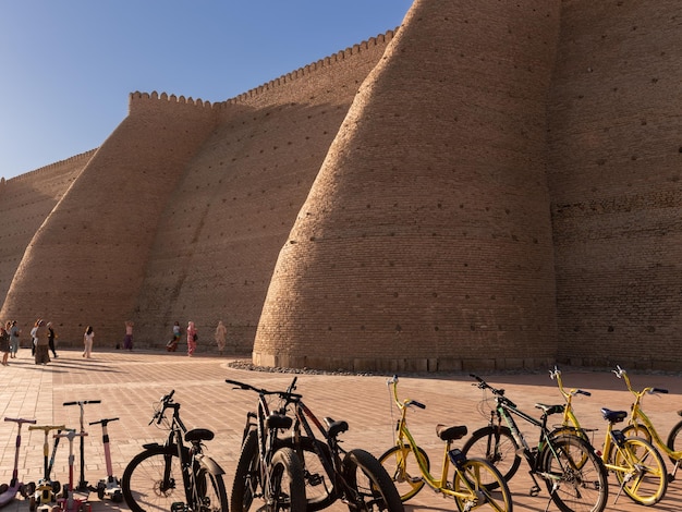 Platz um die alte Zitadelle Ark mit Wanderern und Leihfahrrädern bei Sonnenuntergang Buchara Usbekistan