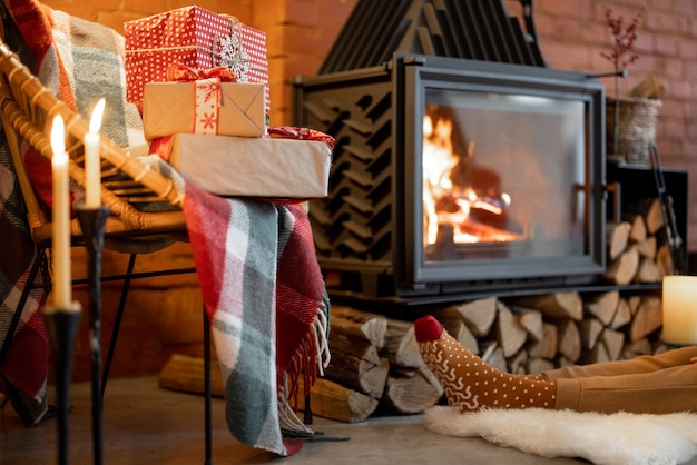 Platzieren Sie an einem brennenden Kamin, der mit Neujahrsgeschenken dekoriert ist, in einem gemütlichen Zuhause