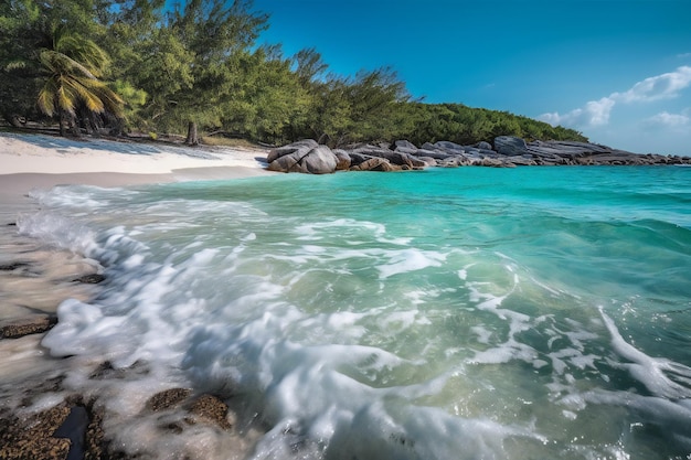 Una playa con agua azul y una playa de arena blanca con una costa rocosa y árboles en el fondo