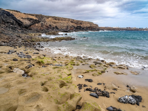 Playa de Aguadulce con arena dorada y piedras en Gran Canaria