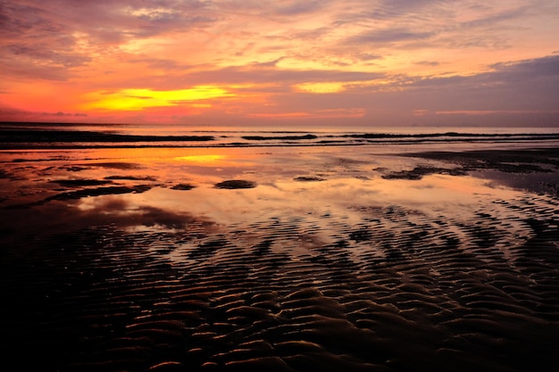 Una playa al atardecer con un cielo colorido y agua.