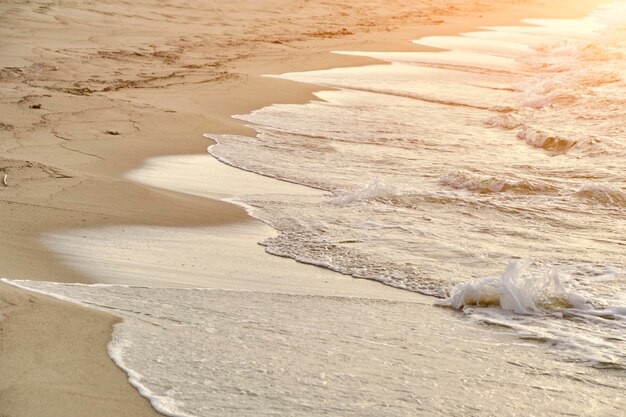 Playa de arena al atardecer y olas onduladas