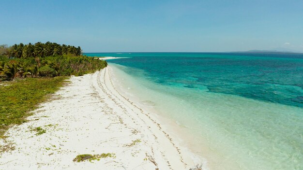 Playa de arena blanca con aguas turquesas por el arrecife de coral del atolón y el mar azul vista aérea de la pequeña isla