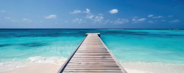 Una playa de arena blanca con un cielo azul tiene un muelle de madera que conduce al océano