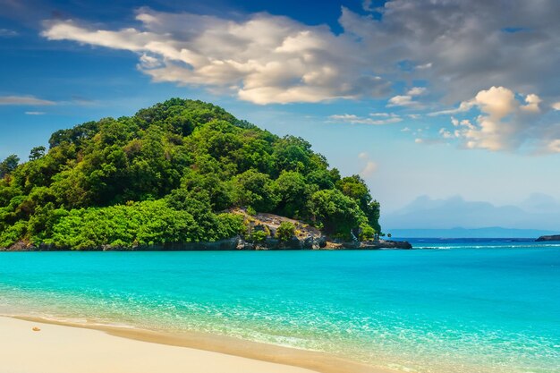 Foto playa de arena donde una isla exuberante se brilla en el resplandor de un cielo de verano