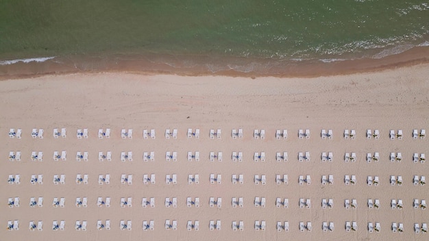 Una playa de arena se extiende a lo largo de la costa adornada con tumbonas vacías Vista aérea