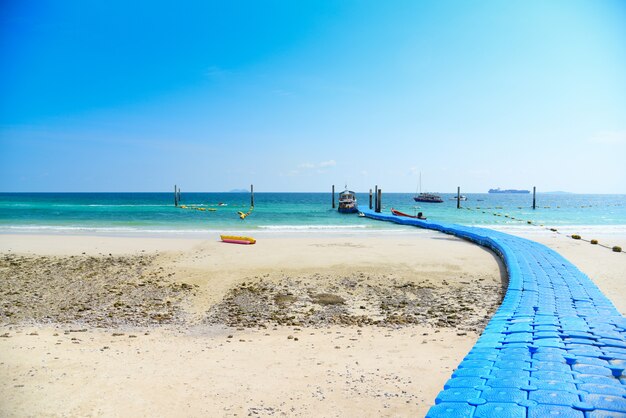 Foto playa, arena, isla tropical de verano, agua azul con cielo brillante y pontón de plástico.