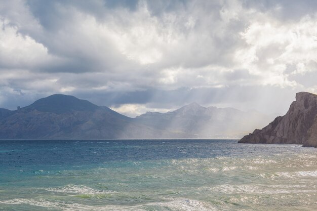 Playa de arena con montañas y cielo nublado